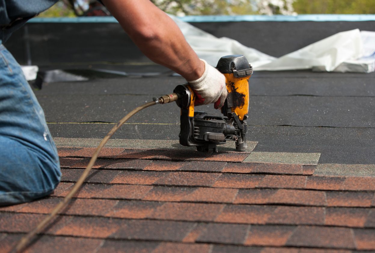 Roofer nailing architectural shingles on a Northwest Side bungalow