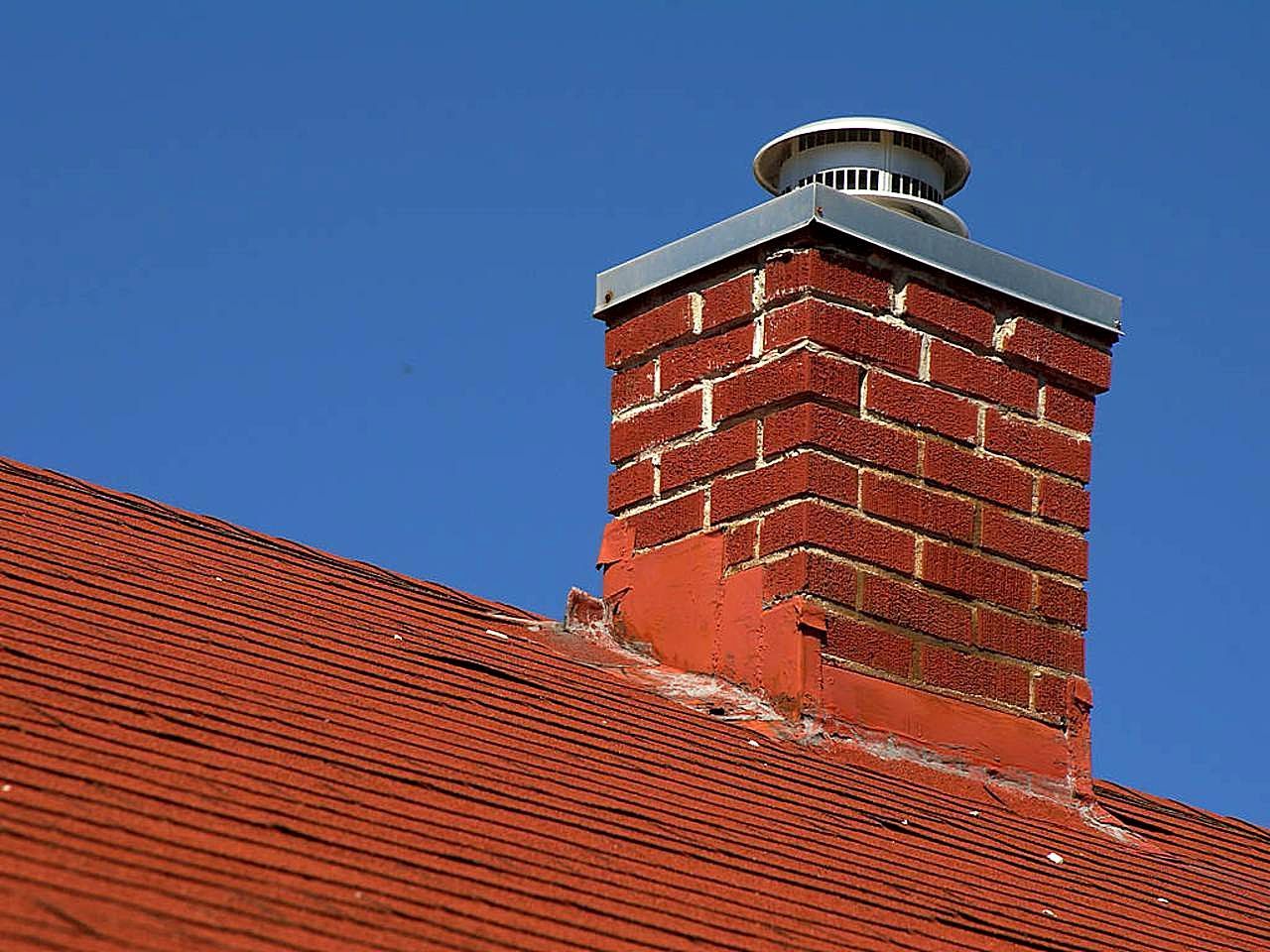 Brick chimney with new metal flashing on a red roof
